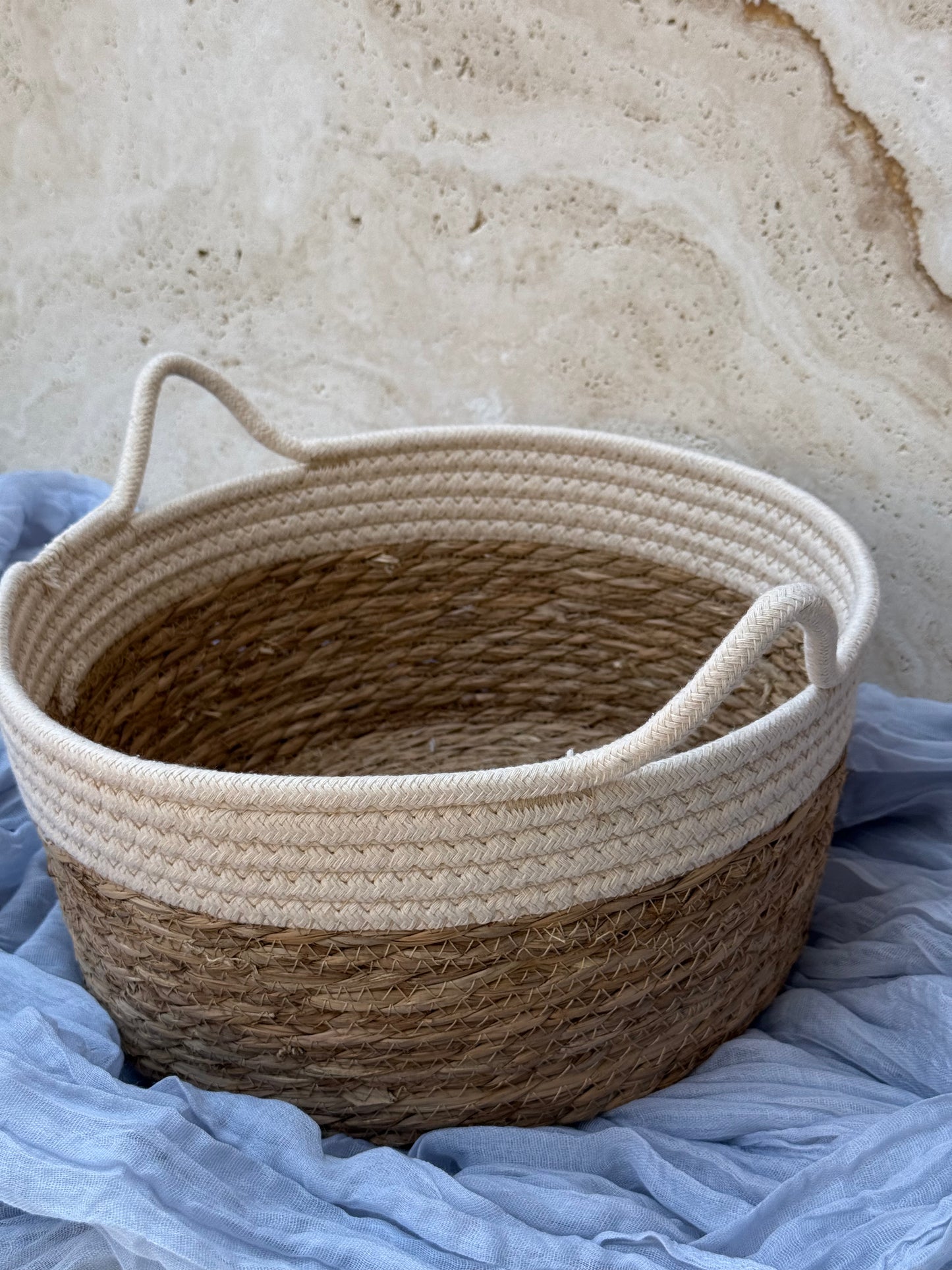 Woven basket with handles on a textured surface