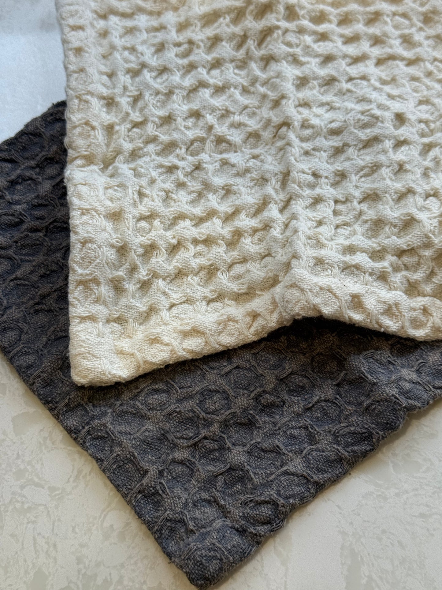 Two cotton cloths in warm neutral hues with soft coastal tones.