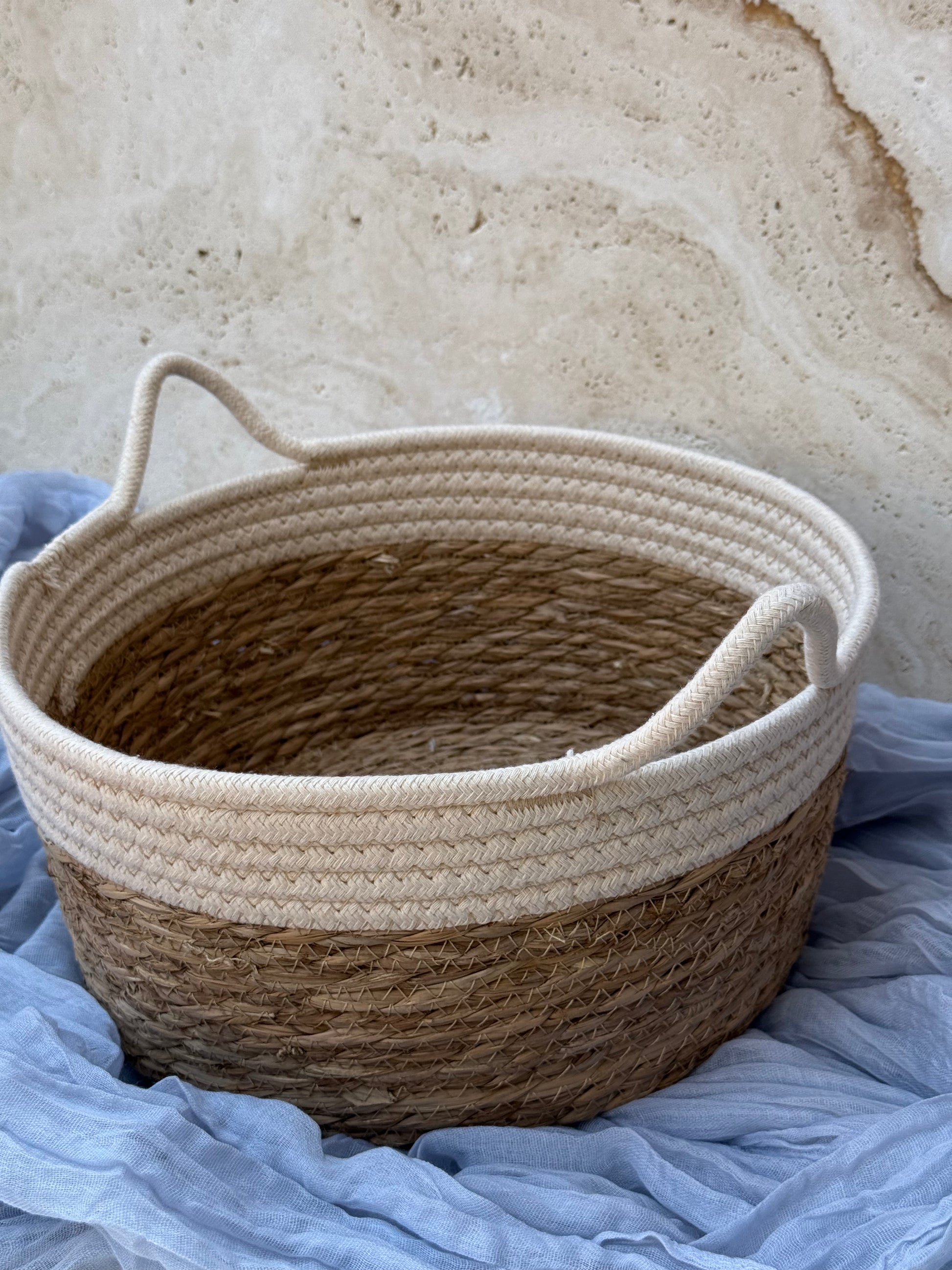 Woven basket with handles on a textured surface